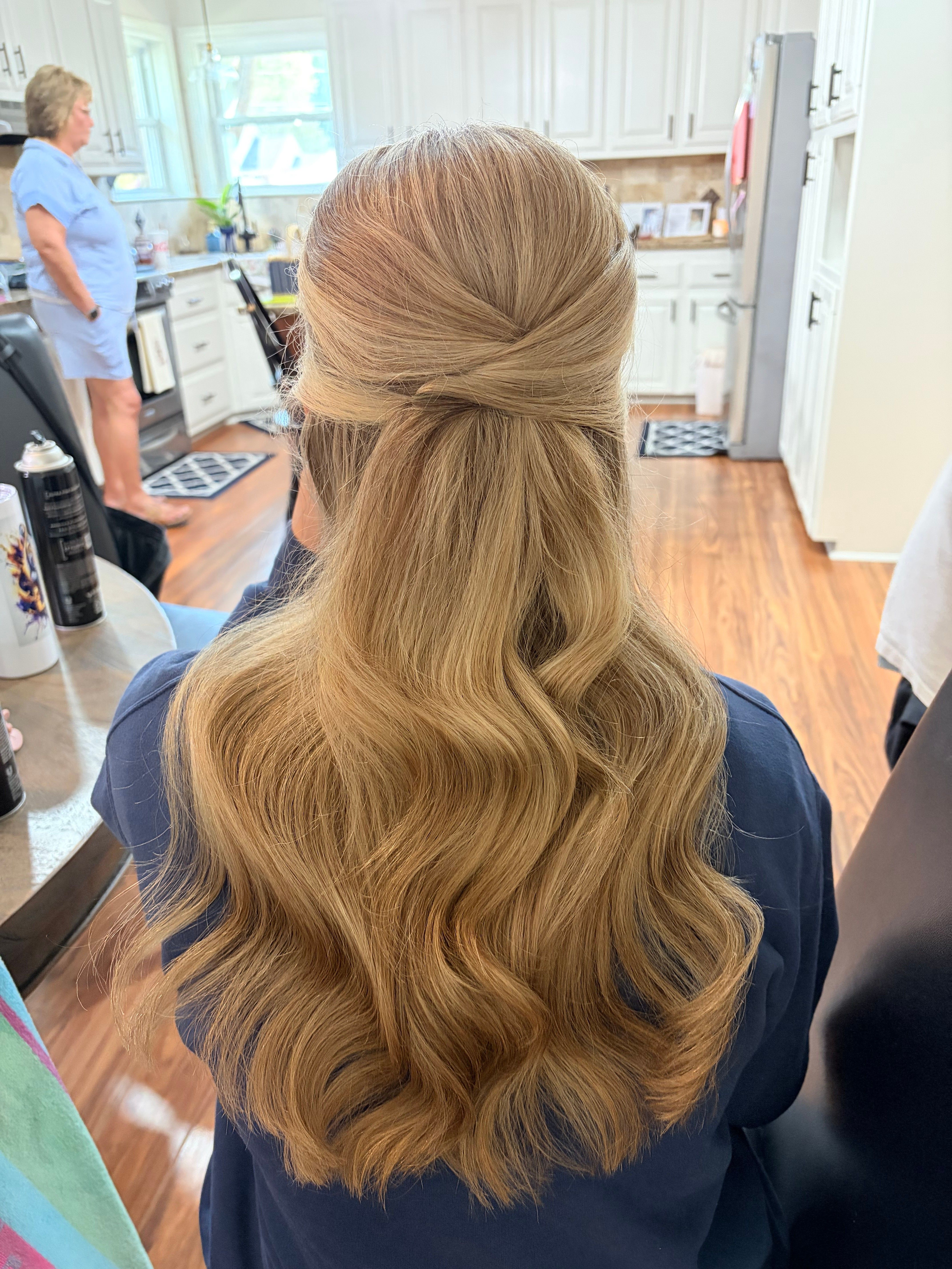 Back view of a blonde half-up twist with long, polished waves