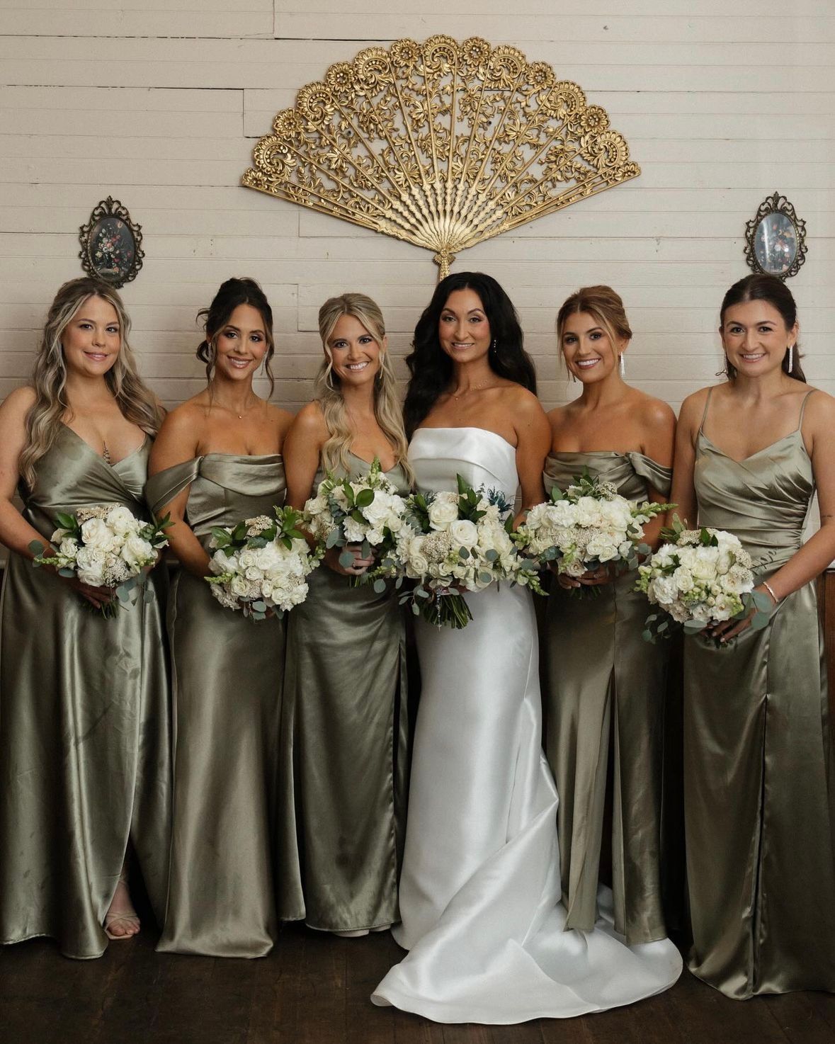 Bride in a strapless satin gown with five bridesmaids in sage satin, each with soft waves or an updo